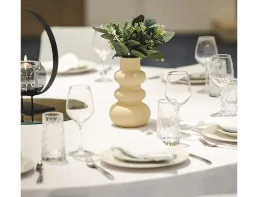 Detalj keramičke vaze sa zelenilom na banket stolu u Hotel Tara sa kristalnim čašama i belim tanjirima