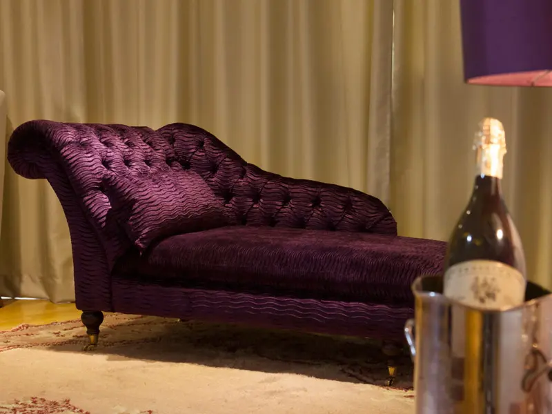 Ljubičasta chaise longue fotelja u Garden Spa Boutique Hotel sa šampanjcem, zlatnom lampom i elegantnim tepihom