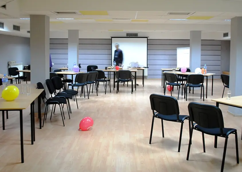 Event sala u Hotel Porta sa stolovima i stolicama u workshop rasporedu, projektorskim platnom i otvorenim prostorom za aktivnosti
