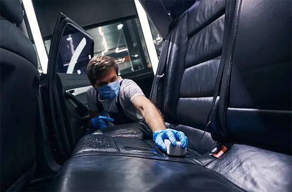 Man applying leather treatment to car seat Man applying leather treatment to car seat