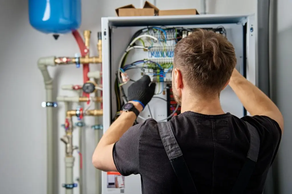 heat pump maintenance guy wearing black shirt inspecting unit 