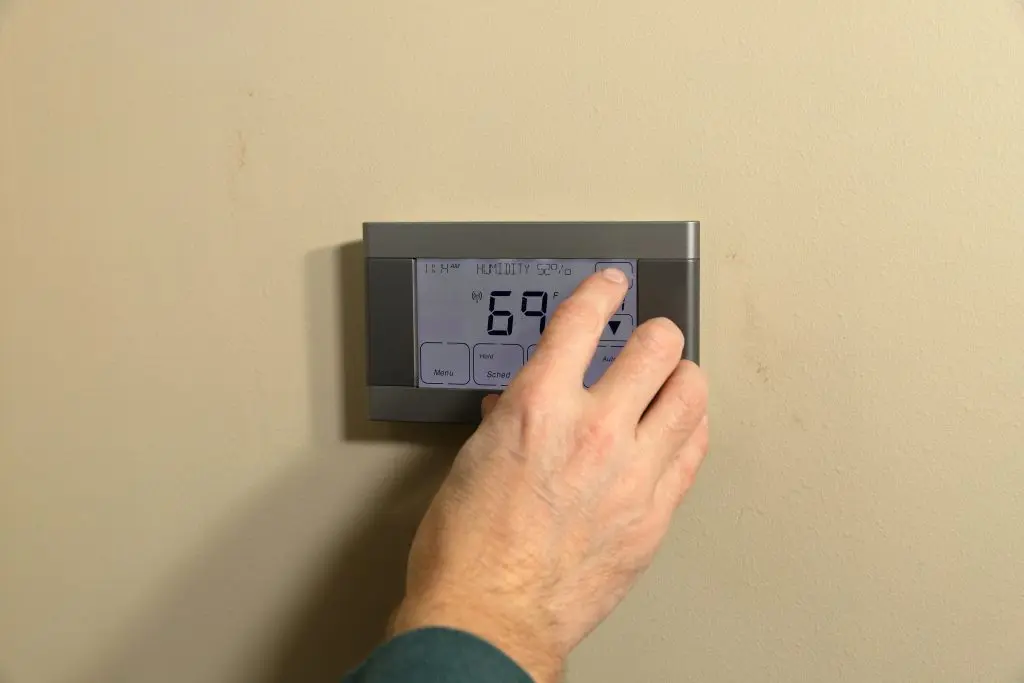 programmable thermostat installation Hand adjusting temperature on digital programmable thermostat