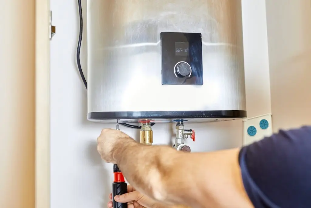 Man tightens the pipe nut in the water heating system. The master installs the water heater. The concept of bathroom maintenance. 