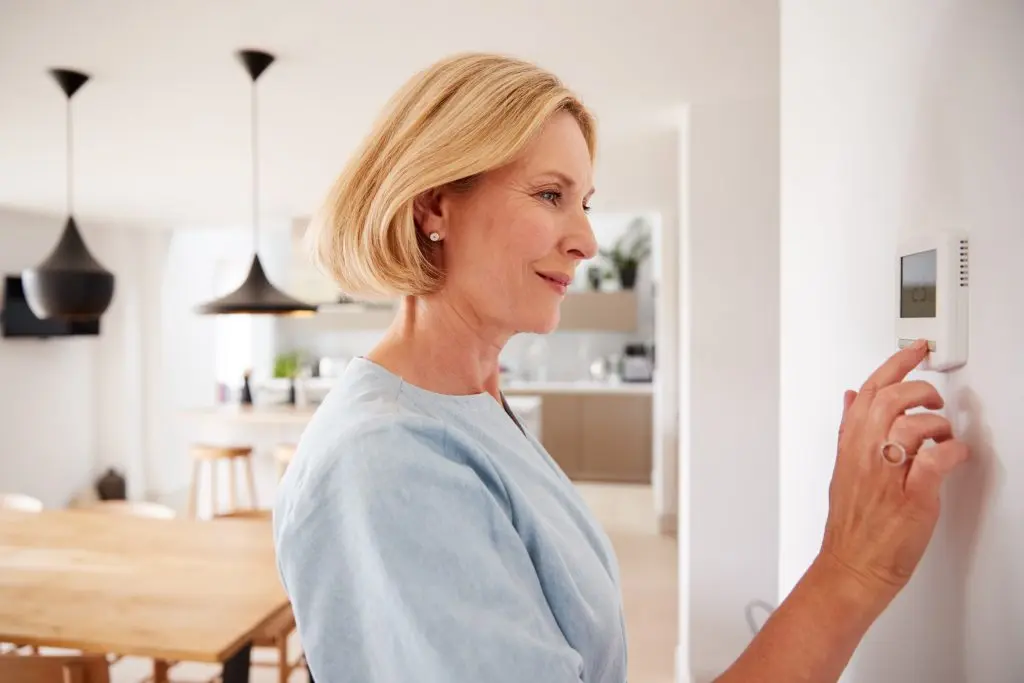 ac not cooling Close Up Of Mature Woman Adjusting Central Heating Temperature At Home On Thermostat
