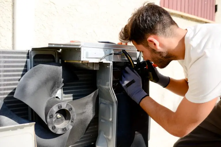 ac compressor replacement cost young man electrician installer working on outdoor compressor unit air conditioner at a client's home