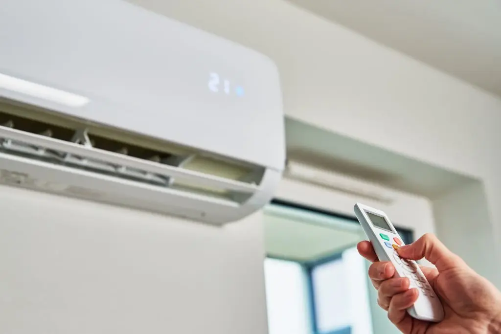 hvac zoning system Hand adjusting temperature on air conditioner with remote control, Working air conditioner for comfort temperature in home at hot summer