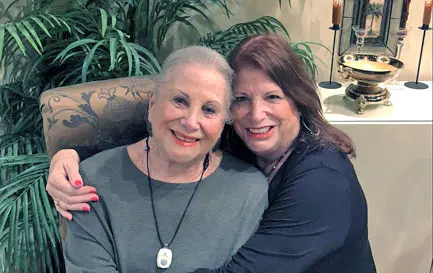 at-home Adult daughter hugging her elderly mother wearing a medical alert pendant