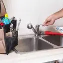 Modern kitchen sink with running faucet and organized tools for HVAC and plumbing maintenance by Carmine's Plumbing.