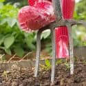 Gardening tools and red rubber boots on a sunny day, showcasing hands-on plant care for home gardens.
