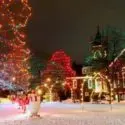 Christmas scene with a lit tree, snowman decor, and a colorfully lit home, showcasing winter festivities for homeowners.