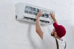 Technician servicing a wall-mounted air conditioning unit, highlighting HVAC maintenance services.