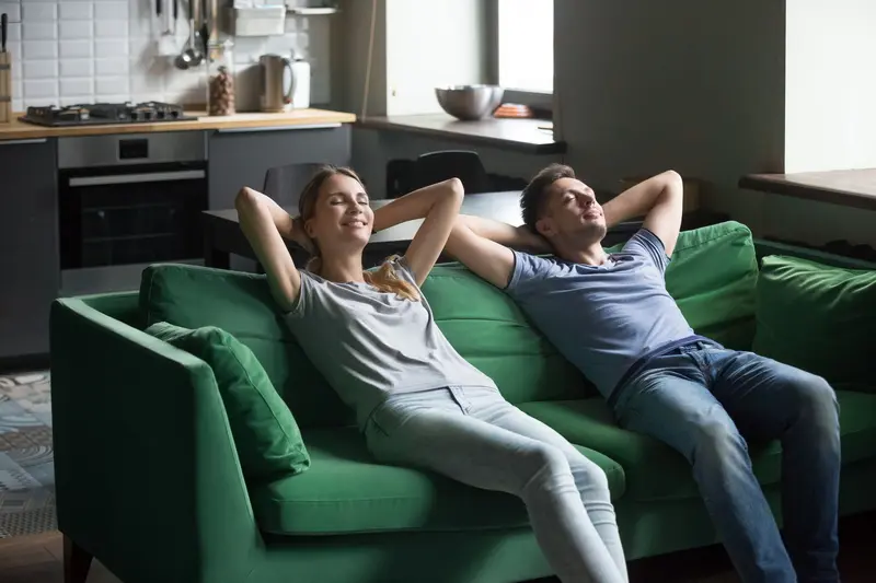 Happy couple leaning on sofa together, stress free weekend concept