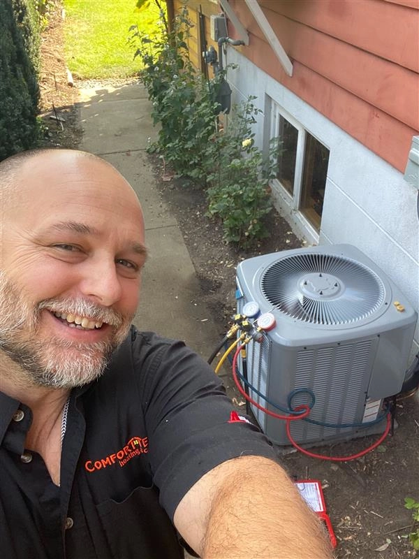 Comfort Tech worker next to heat pump