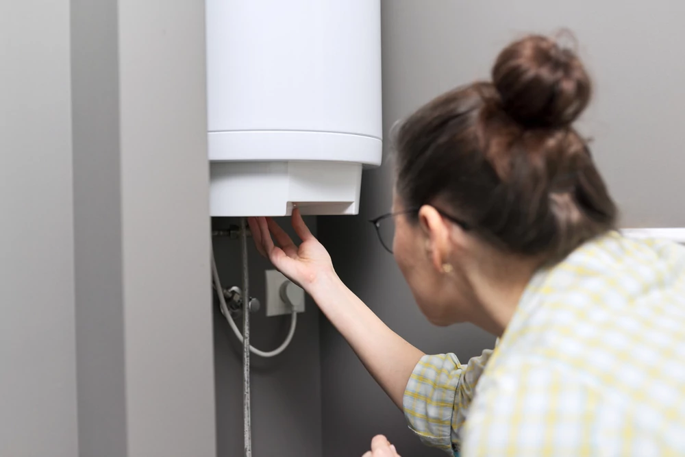 a woman regulates the temperature on an electric water heater