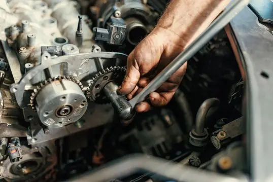 A close-up picture of a young Caucasian mechanic repairing the broken gear mechanism on a car.