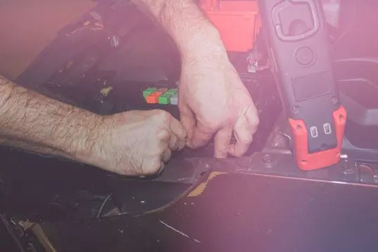 The concept of car service, repair, tuning, maintenance. The car electrician fixes problems in the electronics of the car. Hands of an electrician working with an electrical unit in a car close-up.