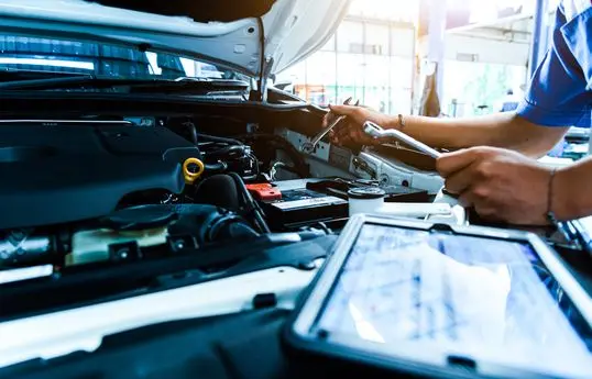 Auto mechanic are checking the condition of the car according to the month. The technician uses the tablet to check.