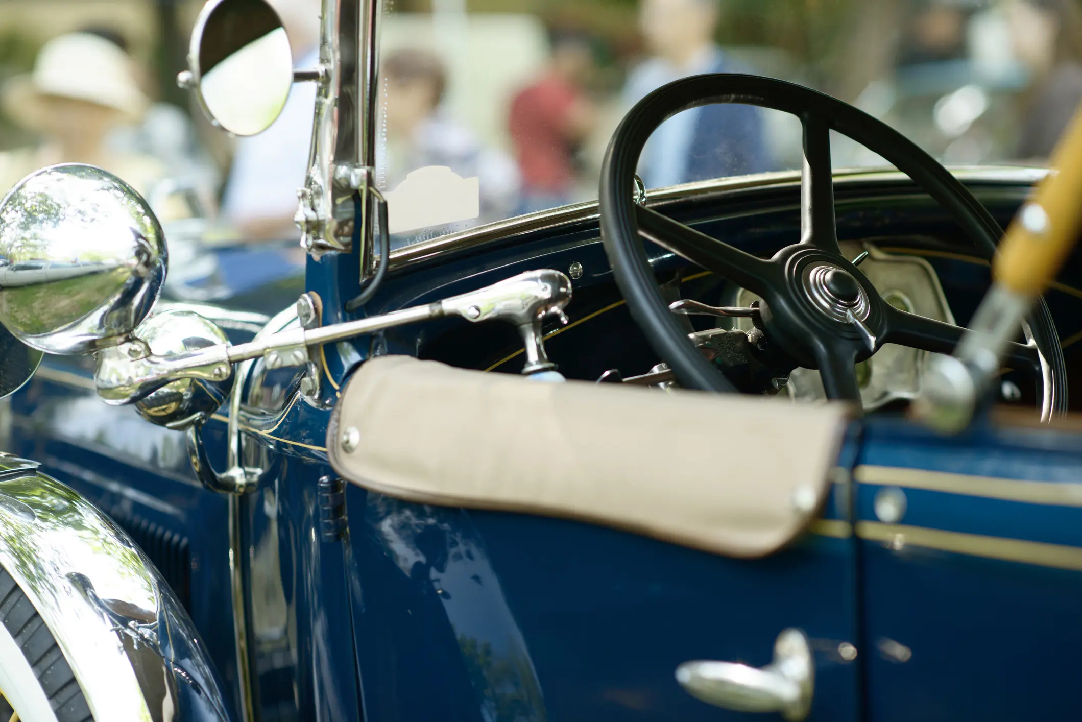 Classic vintage car interior with steering wheel, chrome mirror and open roadster cockpit.