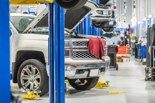 Car Dealership Auto Service Area. Clients Vehicles on Automotive Lifts Under Maintenance. From Oil Change to Complicated Timing Chain Replacement.