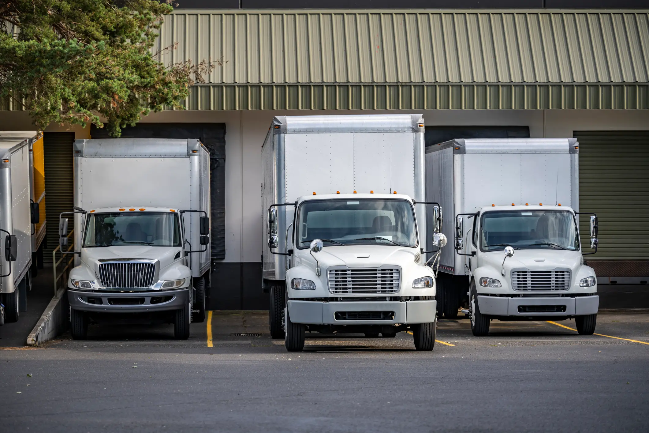 Useful Industrial standard for local deliveries and short haul freights compact middle duty rigs semi trucks with box trailers standing in warehouse dock with gates loading cargo for next delivery