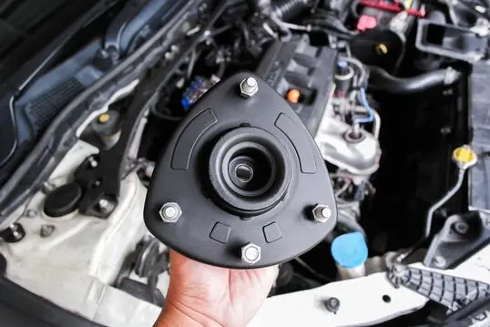 Shock Absorber Strut Mount, Top strut mount of suspension shock absorber strut in mechanic hand.