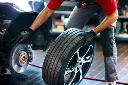 Closeup of a 40's male care mechanic replacing a tire at a car repair shop