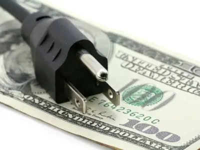Plug on top of a hundred-dollar bill, symbolizing energy costs and savings associated with ductless mini-split systems for lower energy bills.