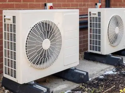Outdoor heat pump units installed on a concrete base, showcasing energy-efficient climate control systems for heating and cooling.