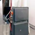 Gray heater unit with visible pipes and connections, illustrating essential HVAC maintenance for optimal home heating efficiency.