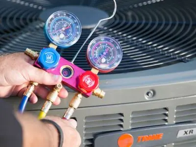 Technician using gauges on an air conditioning unit for maintenance and repair, highlighting HVAC service and efficiency.
