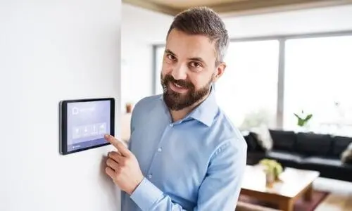 Man adjusting a digital thermostat on a wall, demonstrating HVAC control for home temperature management, relevant to HVAC maintenance tips and services by Mid Florida A/C.