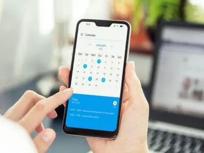 Person using smartphone calendar to schedule AC maintenance appointment for spring service.