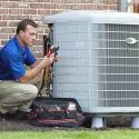 HVAC technician servicing an air conditioning unit outside a home, illustrating maintenance and repair services offered by Mid Florida A/C.