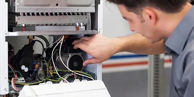 Technician inspecting HVAC system wiring and components.