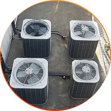 Four outdoor HVAC units on a concrete surface next to a building.
