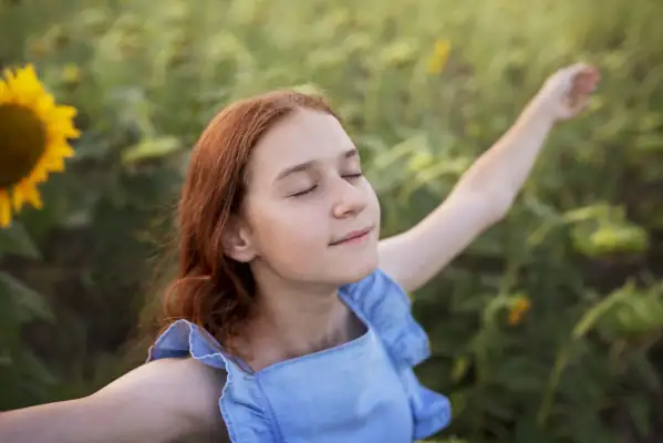 The Advantages of Energy-Efficient AC Systems: Why They're a Smart Investment - Girl with eyes closed in the middle of sunflower field. Arms outstretched.
