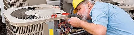 Technician repairing air conditioning unit, showcasing plumbing and HVAC expertise relevant to RupCoe Plumbing's services.