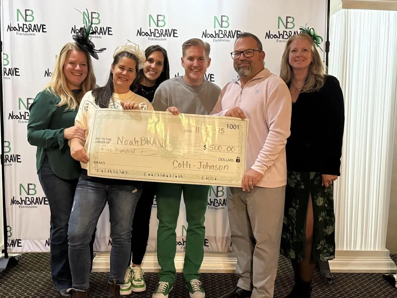 Cotti-Johnson HVAC representatives presenting a $500 donation check to the NoahBRAVE Foundation, surrounded by supporters, at a community event.