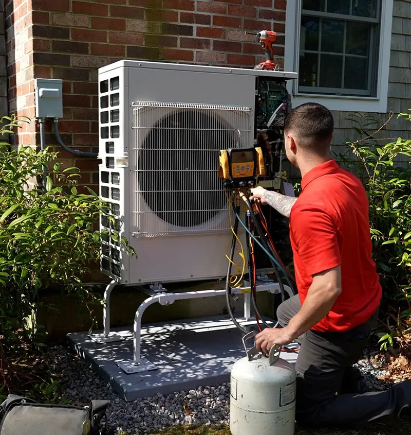HVAC technician servicing an air conditioning unit outside a home in Taunton, MA, showcasing expertise in heating and cooling systems.