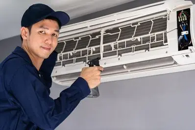 Technician cleaning air conditioning unit, ensuring HVAC system efficiency and maintenance for home comfort.