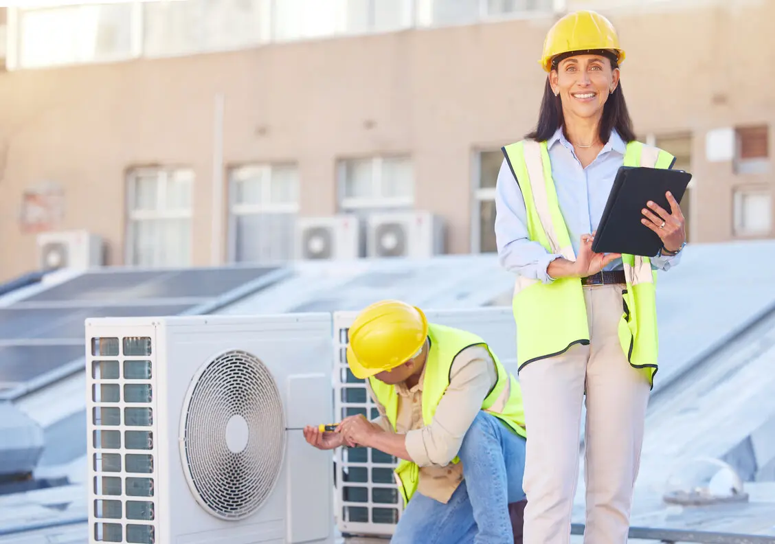 HVAC technicians in safety gear performing installation and maintenance on an outdoor air conditioning unit, emphasizing professional HVAC services in Victoria, MN.