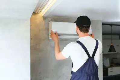 Technician installing a modern air conditioning unit on a concrete wall, highlighting HVAC service expertise relevant to seasonal maintenance.
