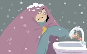 Person wrapped in a blanket with snowflakes, looking frustrated while trying to turn on a frozen faucet, illustrating the challenges of dealing with frozen pipes in winter.