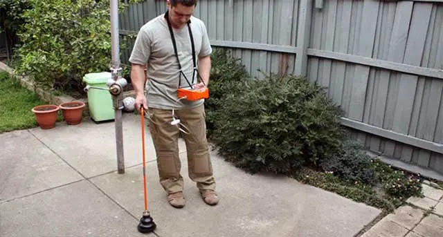 Man using a leak detection device in a residential yard, highlighting plumbing expertise and leak repair services by Jim Wagner Plumbing, Inc.