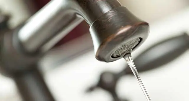Close-up of a kitchen faucet with water flowing, emphasizing faucet repair and replacement services by Jim Wagner Plumbing in Wheaton, IL.