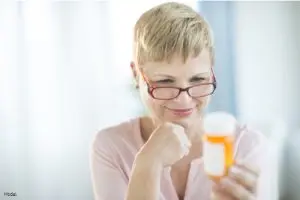 Mature woman reading the information on a pill bottle