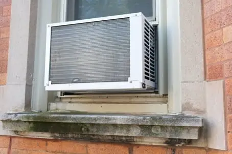 Window air conditioner unit installed in a residential window, highlighting the importance of maintenance for efficient cooling and energy savings.