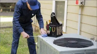 Technician performing maintenance on an outdoor air conditioning unit, emphasizing HVAC service and repair expertise.