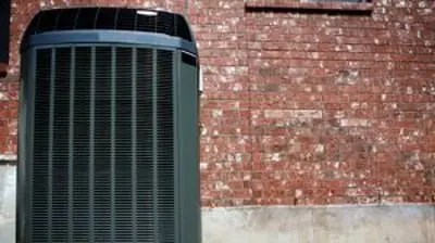 Air conditioning unit against a brick wall, representing AQS Heating & Air Conditioning's installation services and expertise in air conditioning systems.
