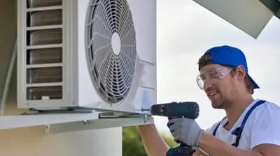 Technician installing air conditioning unit, emphasizing HVAC maintenance and repair services by AQS Heating & Air Conditioning.